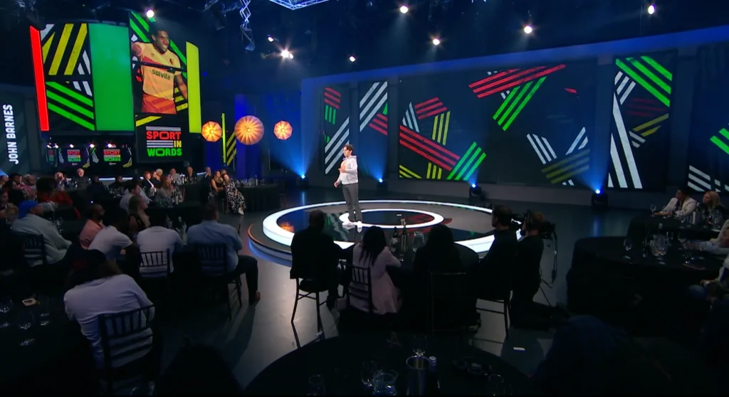 Joseph Roberts performing One Common Goal beneath a portrait of John Barnes