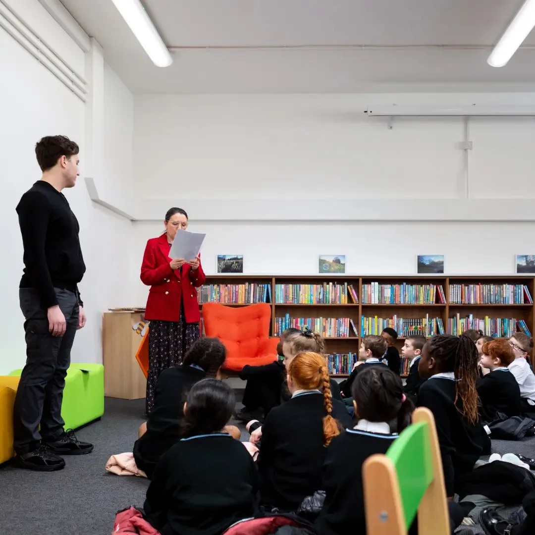 Joseph Roberts alongside an adult reading to younger pupils in a library