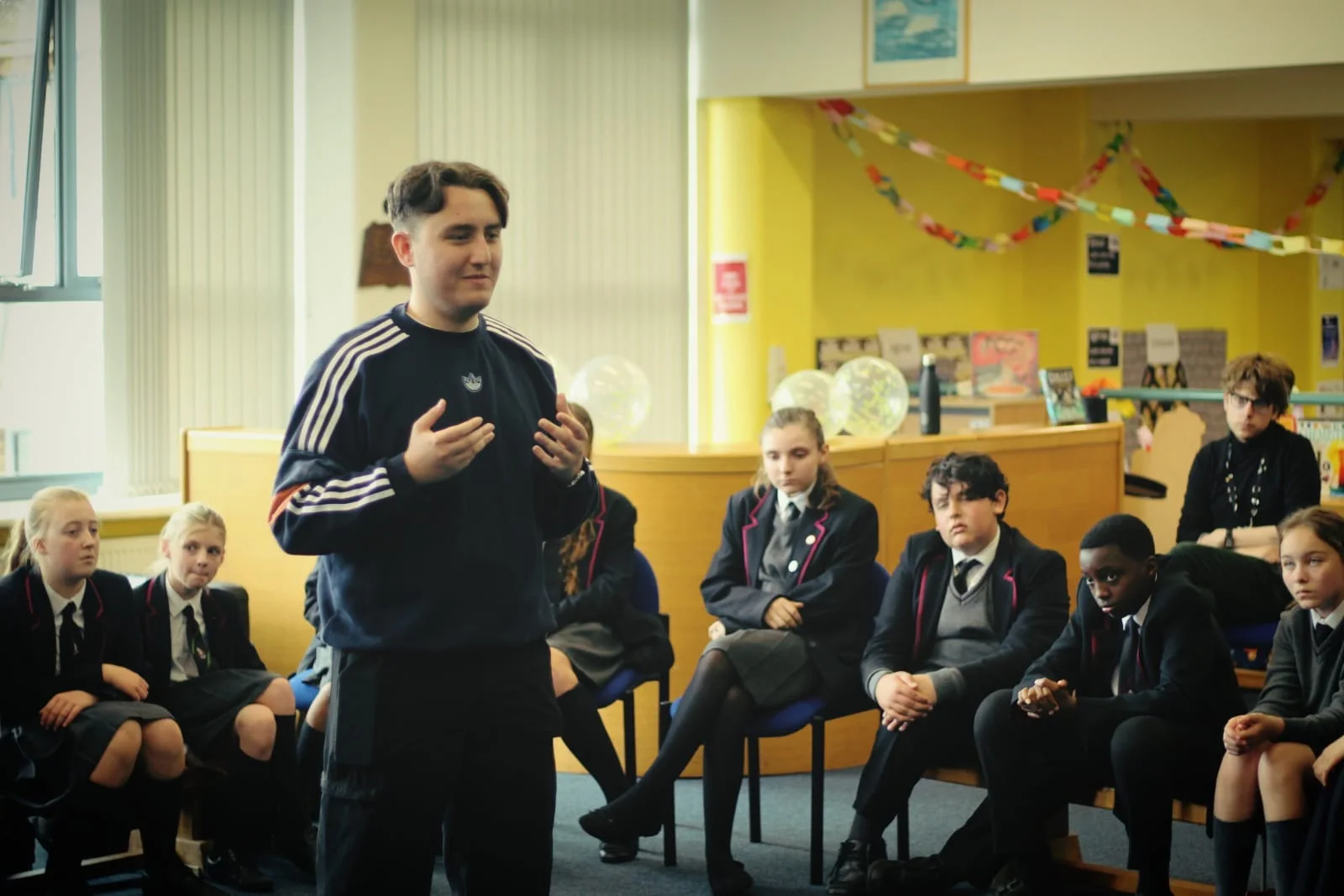 Joseph Roberts speaking with pupils seated around him in a school library