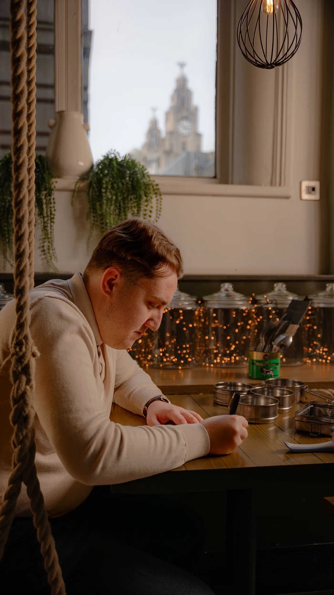 Joseph Roberts writing at a table overlooking Liverpool